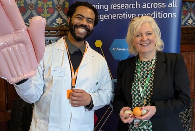 A scientist with an inflatable hand poses with an MP