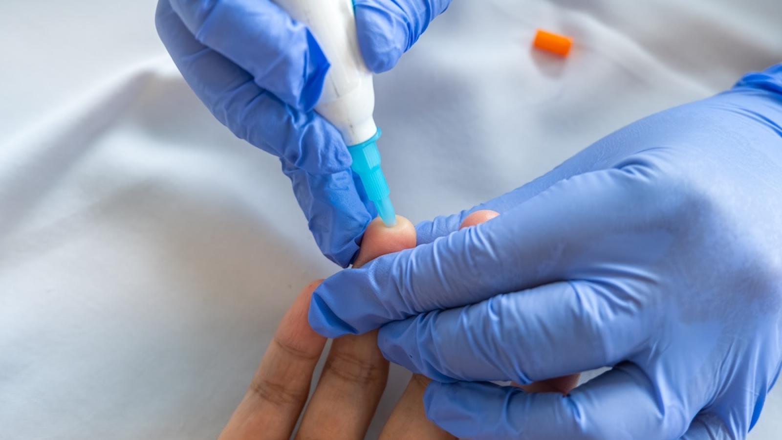 Healthcare worker taking a finger prick blood sample from a patient