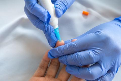 Healthcare worker taking a finger prick blood sample from a patient