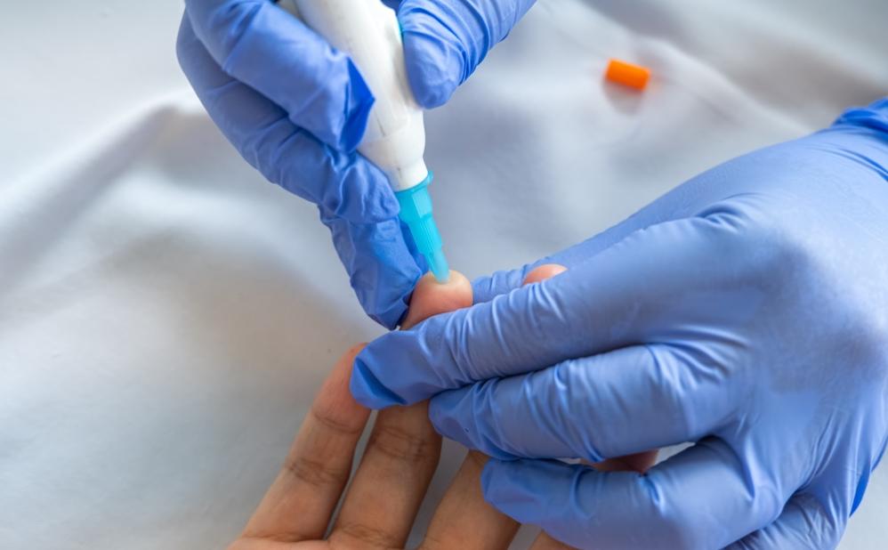 Healthcare worker taking a finger prick blood sample from a patient