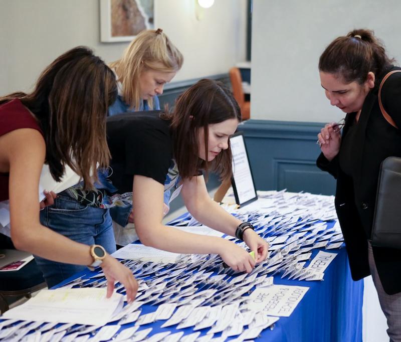 People finding badges for an event on a front desk