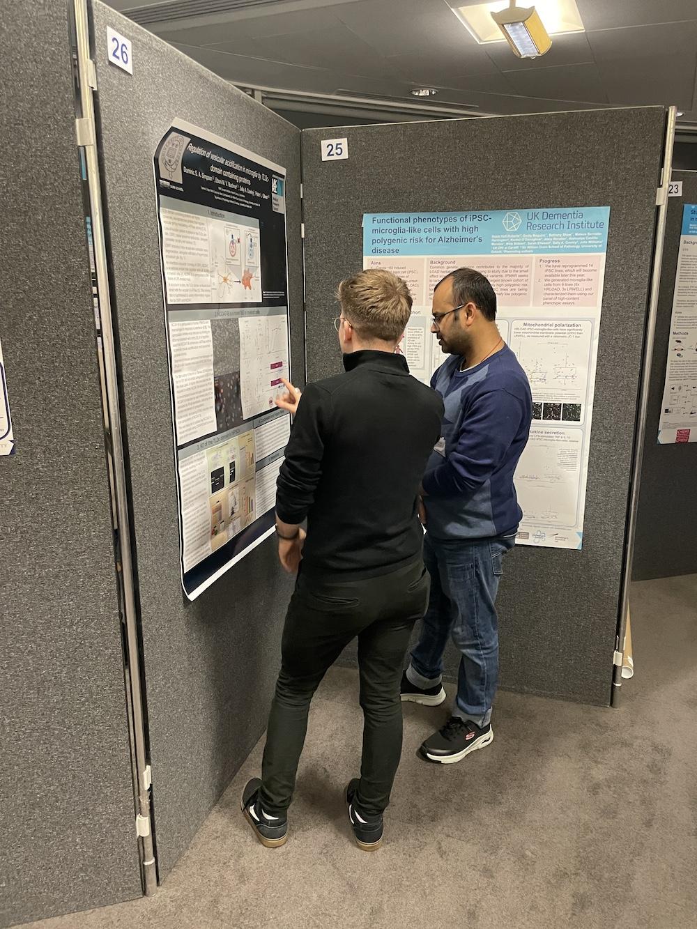 Two people stand in front of a scientific poster at a conference